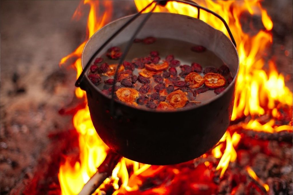 pot of food cooks on a campfire