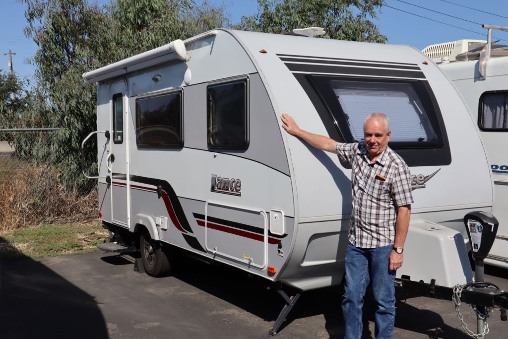 a man stands in front of a Lance 1475 travel trailer