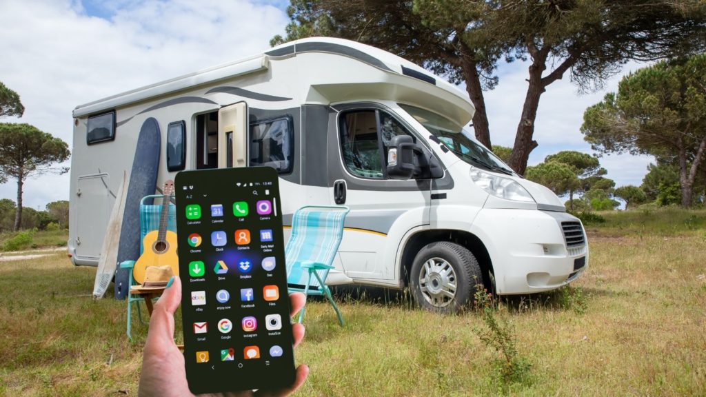 person holds phone in front of a class b RV