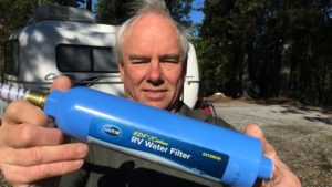 man holding an RV water filter toward the camera