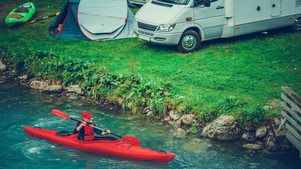a kayaker paddles near an RV and tent in a dispersed campsite