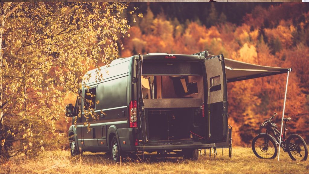a camper van in parked at a campsite in the fall
