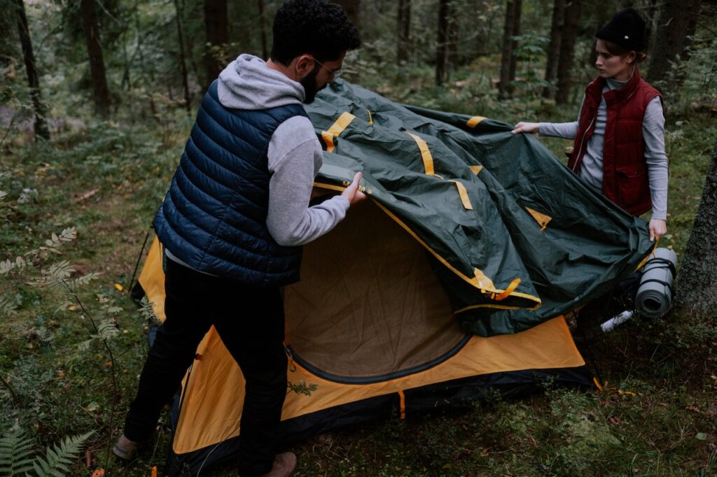 A couple puts up a tent at a campsite