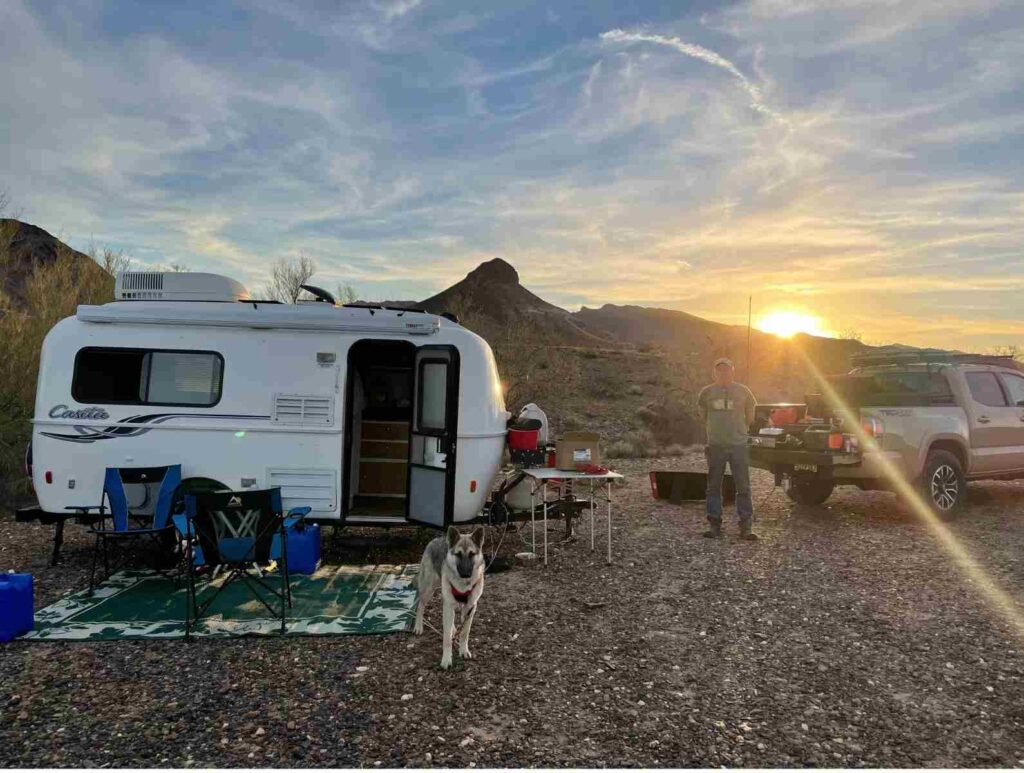 A man and a dog stand outside a Casita Trailer in Quartzsite Arizona in a dispersed campsite