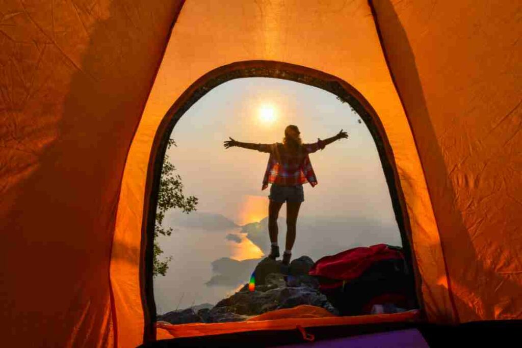A woman stands outside of a tent