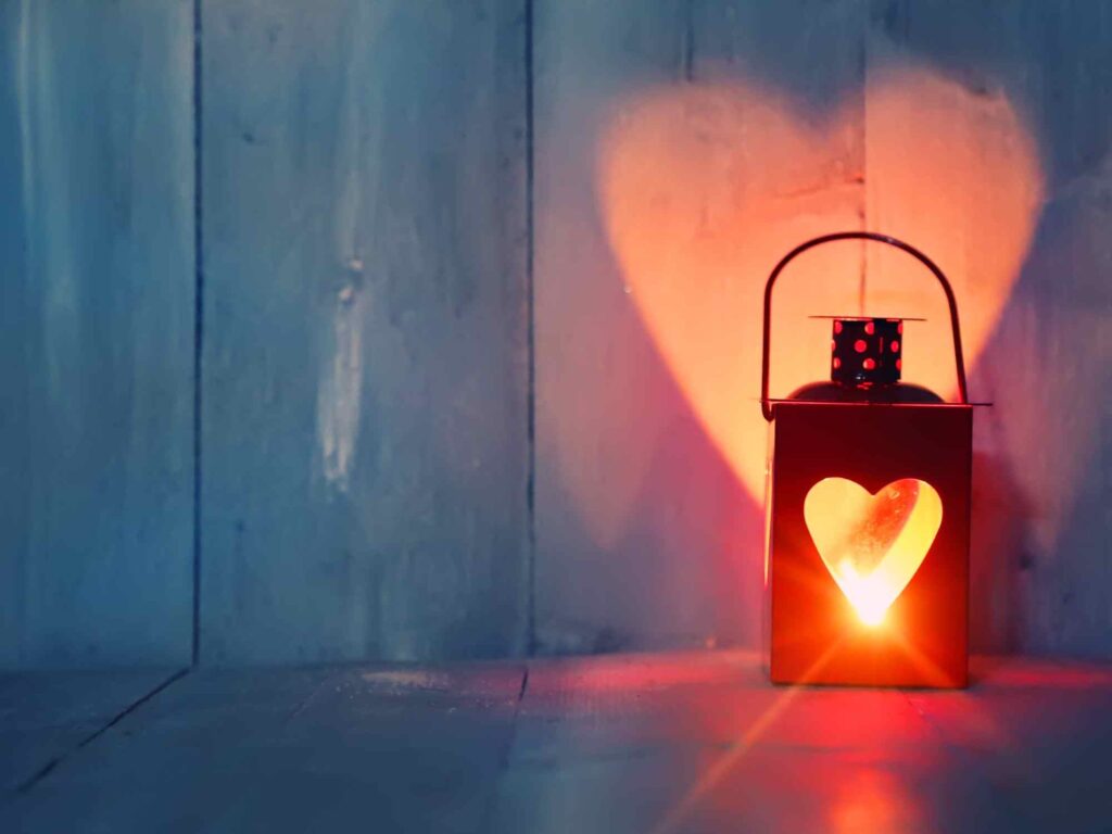 a heart-shaped lantern reflects a warm glow on the wall behind it
