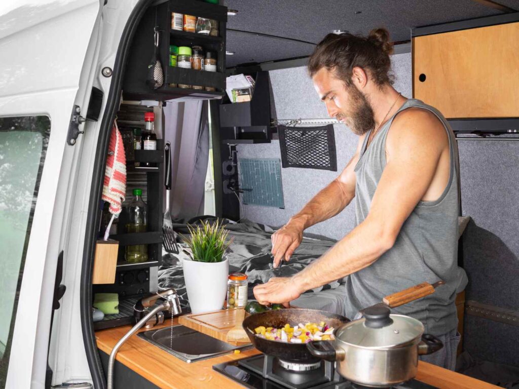 a man cooking in a camper van