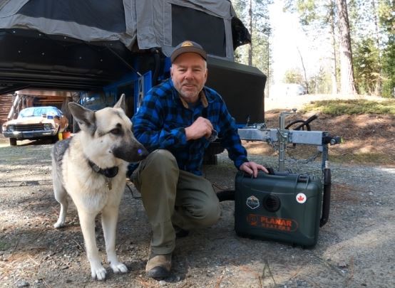 Man and dog with a diesel heater in front of camper trailer